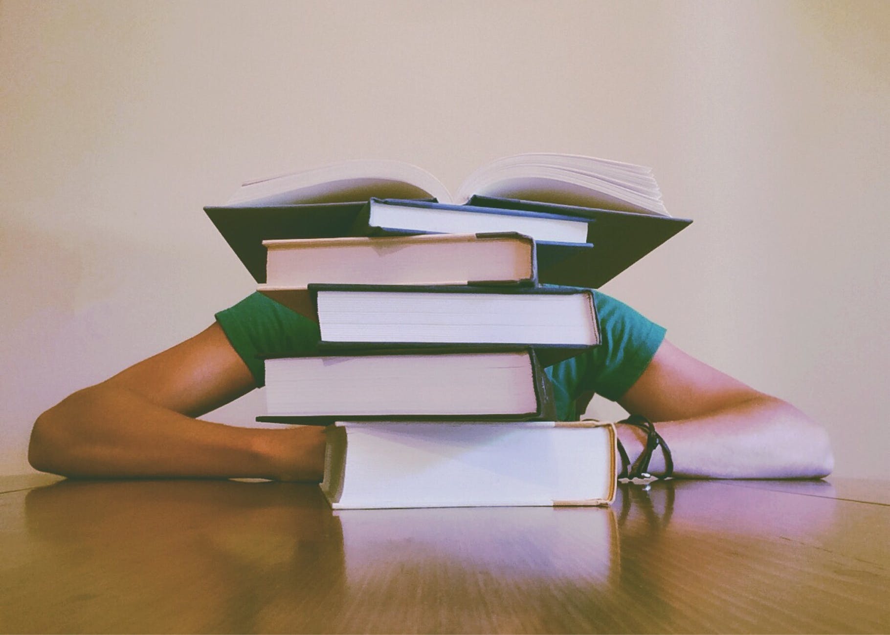 Woman hiding behind a stack of books. 